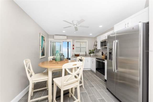 kitchen featuring wood finish floors, baseboards, white cabinets, light countertops, and appliances with stainless steel finishes