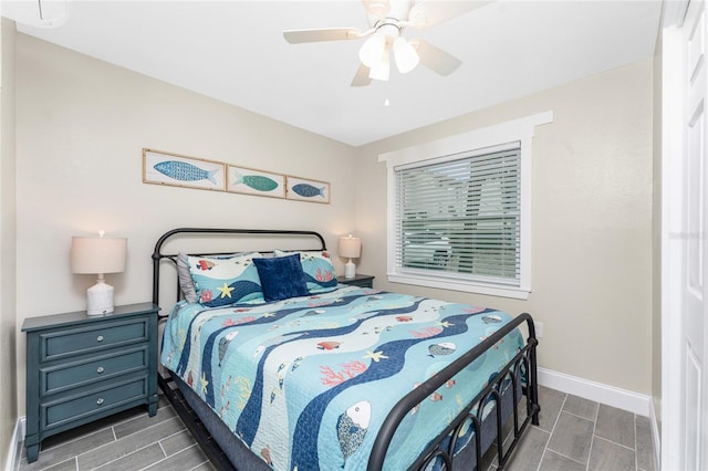 bedroom with a ceiling fan, wood finish floors, and baseboards