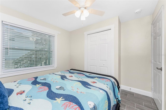 bedroom with ceiling fan, wood tiled floor, baseboards, and a closet