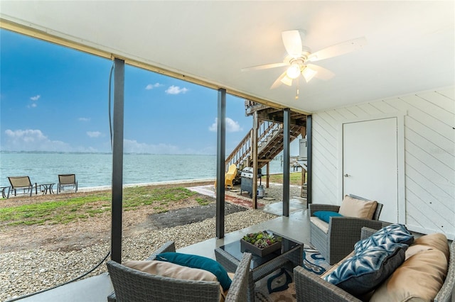 sunroom with ceiling fan and a water view