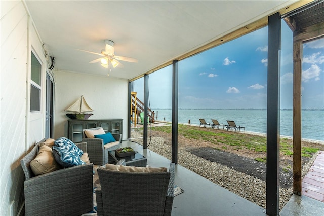 sunroom featuring a water view and a ceiling fan