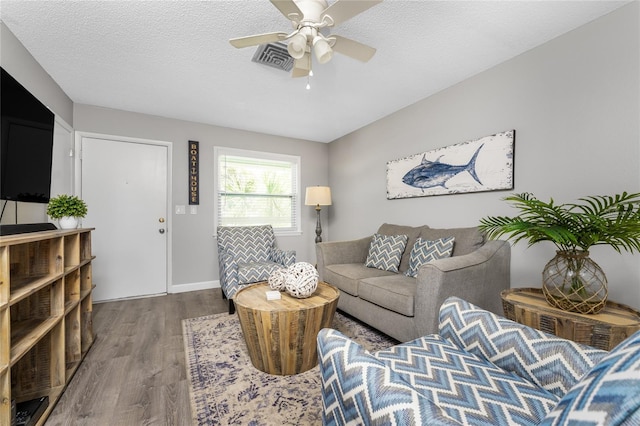 living room featuring visible vents, ceiling fan, a textured ceiling, and wood finished floors