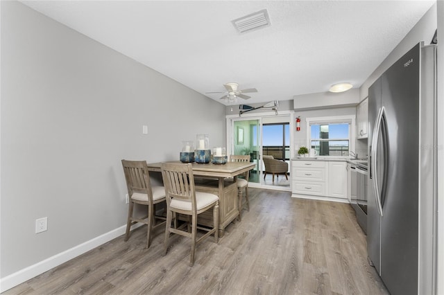 dining space with visible vents, ceiling fan, light wood-style flooring, and baseboards