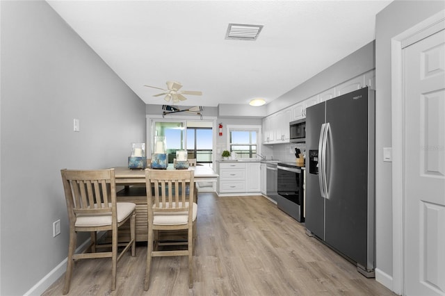 kitchen featuring stainless steel appliances, visible vents, white cabinetry, ceiling fan, and light wood-type flooring