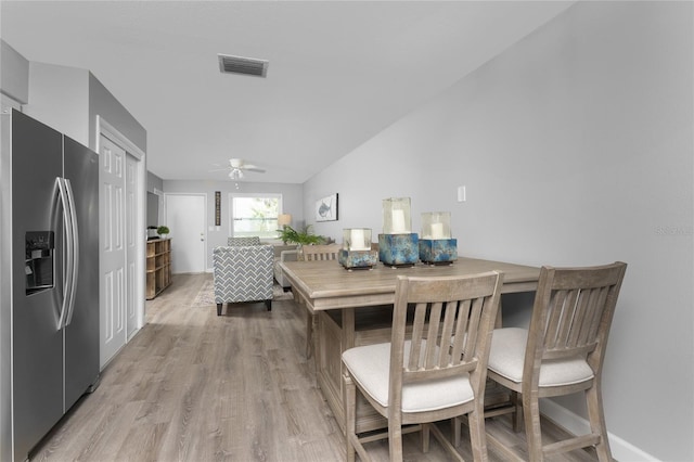 kitchen featuring stainless steel refrigerator with ice dispenser, light wood finished floors, lofted ceiling, visible vents, and ceiling fan