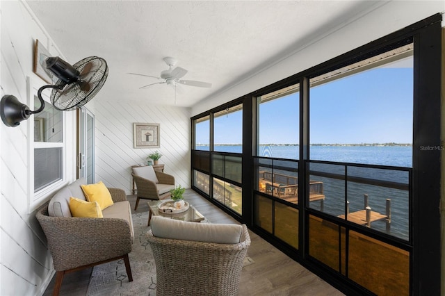 sunroom featuring a ceiling fan, a wealth of natural light, and a water view