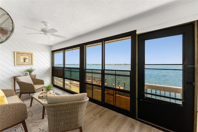 sunroom with a water view and a ceiling fan