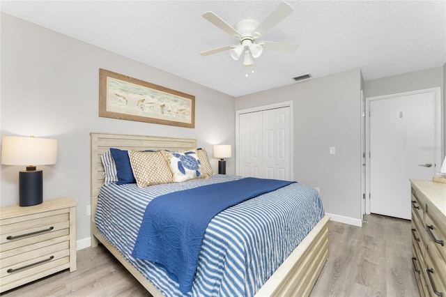 bedroom with a closet, visible vents, a textured ceiling, and wood finished floors