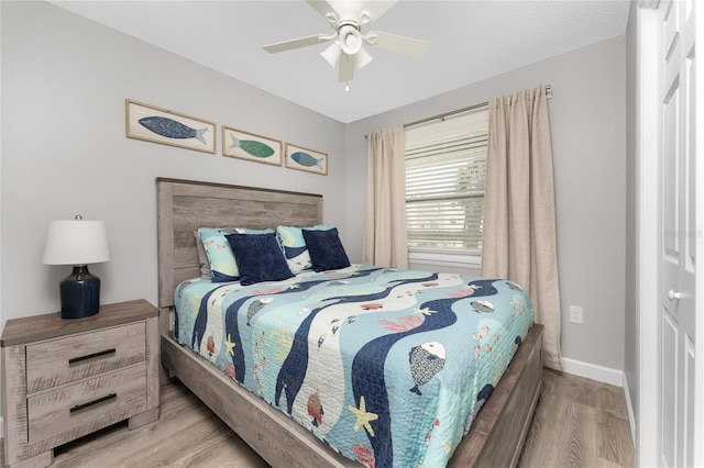 bedroom with wood finished floors, a ceiling fan, and baseboards