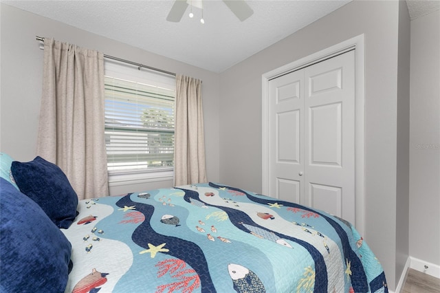 bedroom with a closet, a ceiling fan, a textured ceiling, wood finished floors, and baseboards