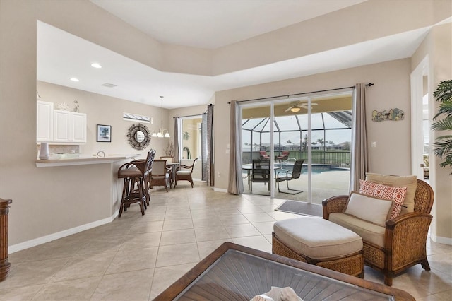 living room with light tile patterned floors, recessed lighting, a sunroom, and baseboards