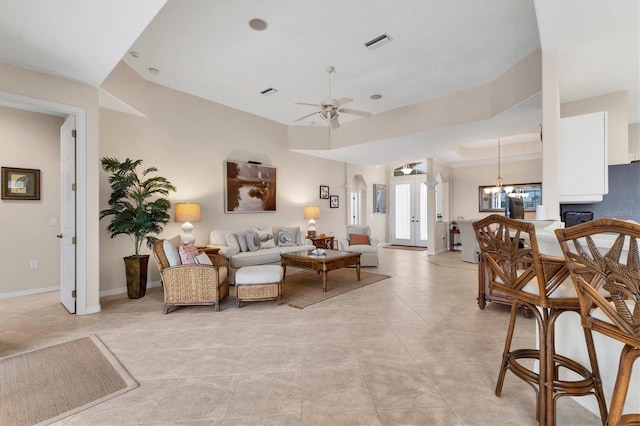 living room featuring light tile patterned flooring, visible vents, baseboards, and ceiling fan with notable chandelier