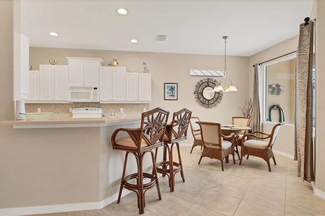 kitchen featuring visible vents, white microwave, light countertops, white cabinetry, and pendant lighting