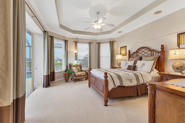 bedroom featuring a raised ceiling, a ceiling fan, light colored carpet, ornamental molding, and access to exterior