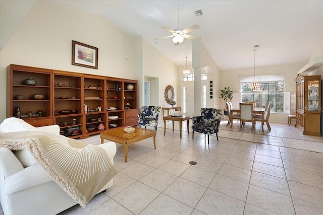 living area featuring high vaulted ceiling, light tile patterned floors, visible vents, and ceiling fan with notable chandelier