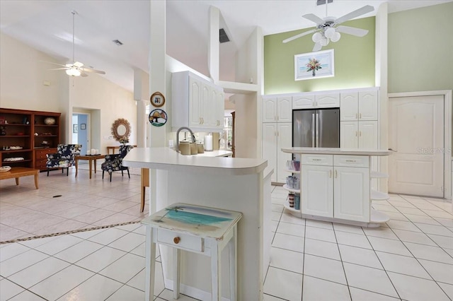 kitchen featuring light tile patterned floors, light countertops, stainless steel fridge, a peninsula, and a kitchen breakfast bar