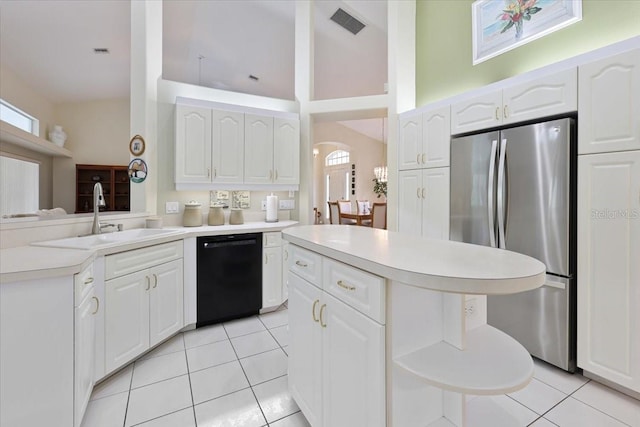 kitchen with light tile patterned floors, black dishwasher, a sink, and freestanding refrigerator