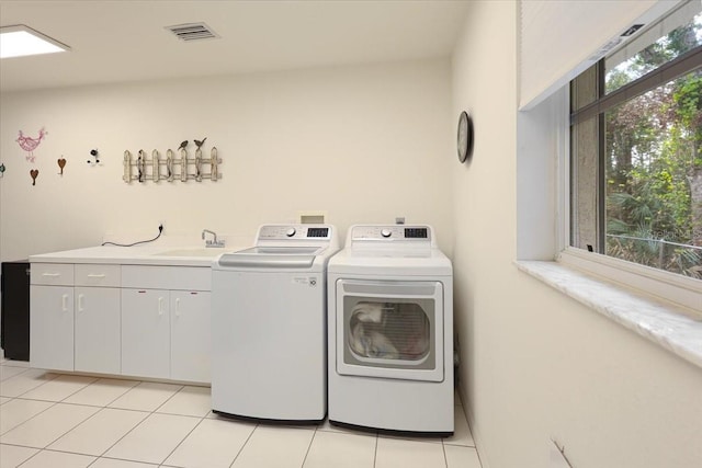 washroom with a wealth of natural light, washing machine and dryer, visible vents, and a sink