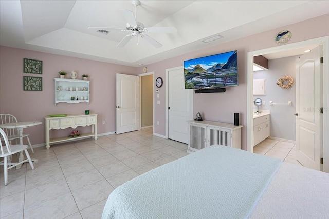 bedroom with light tile patterned floors, a raised ceiling, visible vents, connected bathroom, and baseboards