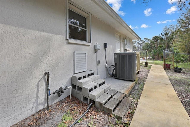 view of property exterior with entry steps, fence, cooling unit, and stucco siding