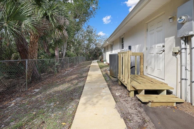 view of property exterior featuring stucco siding, fence, and central air condition unit