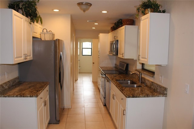 kitchen featuring stainless steel appliances, recessed lighting, white cabinets, a sink, and dark stone countertops