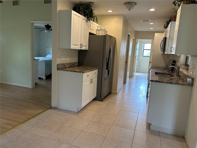 kitchen with light tile patterned floors, appliances with stainless steel finishes, a sink, and white cabinets