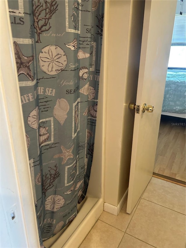 full bath with curtained shower, baseboards, and tile patterned floors