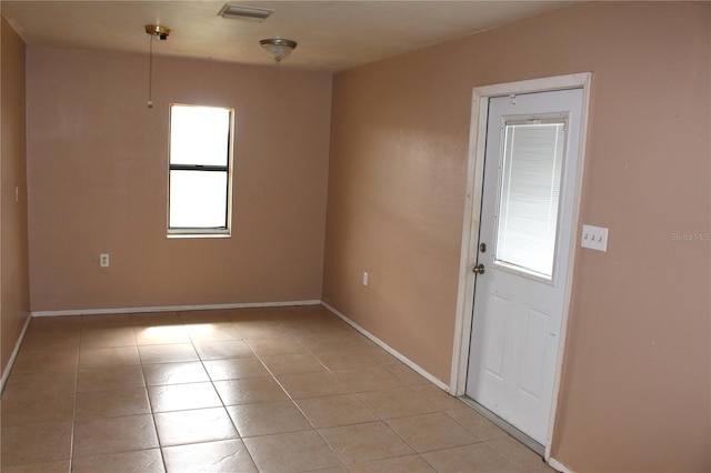 unfurnished room featuring light tile patterned flooring, visible vents, and baseboards