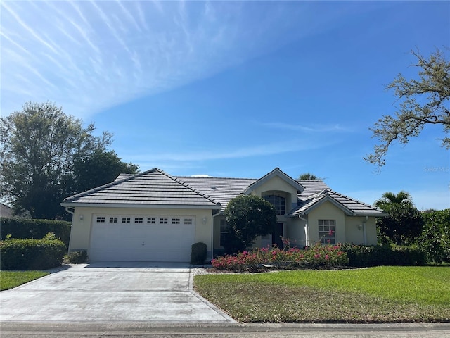 ranch-style home with driveway, stucco siding, a garage, and a front yard