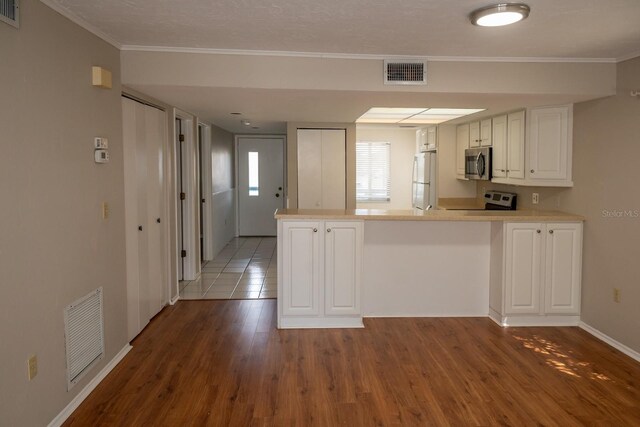 kitchen featuring a peninsula, visible vents, appliances with stainless steel finishes, and wood finished floors