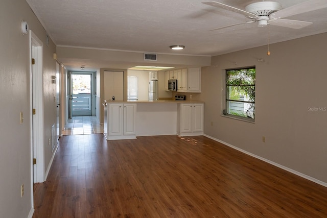 kitchen featuring visible vents, white cabinets, dark wood finished floors, stainless steel microwave, and freestanding refrigerator