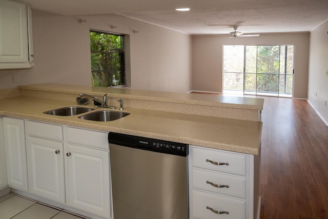 kitchen featuring open floor plan, a peninsula, stainless steel dishwasher, white cabinetry, and a sink