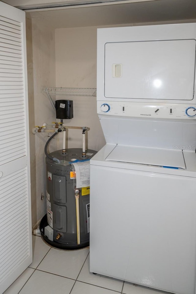 laundry room featuring laundry area, water heater, stacked washing maching and dryer, and light tile patterned flooring