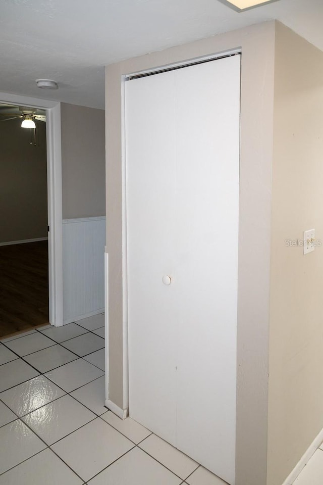 corridor featuring light tile patterned floors and a wainscoted wall