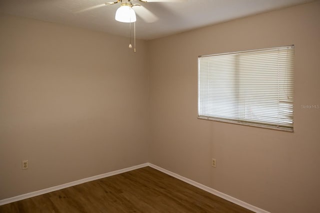 spare room featuring a ceiling fan, baseboards, and dark wood-type flooring