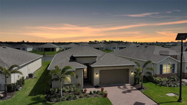 view of front of property featuring a garage, a residential view, decorative driveway, a front lawn, and stucco siding