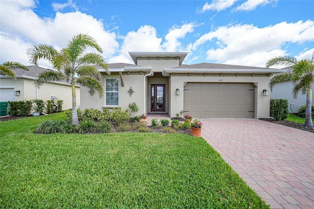 prairie-style home featuring a garage, a front yard, decorative driveway, and stucco siding