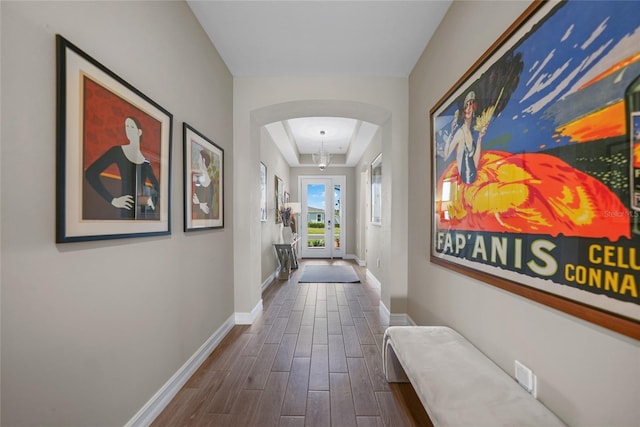 hall featuring baseboards, arched walkways, and dark wood finished floors