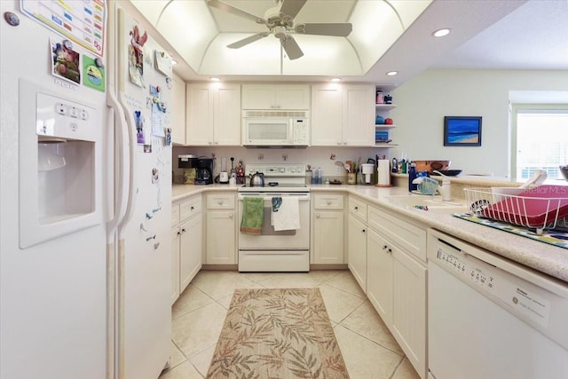 kitchen featuring a tray ceiling, light tile patterned floors, light countertops, a sink, and white appliances