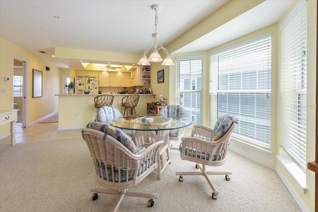 dining room with light carpet, ceiling fan, plenty of natural light, and baseboards