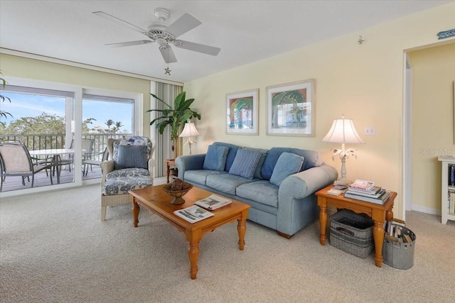 living area featuring carpet, baseboards, and a ceiling fan