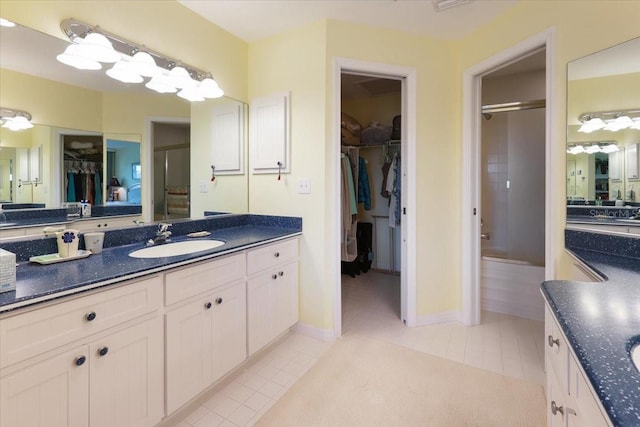 bathroom with baseboards, a shower with shower door, tile patterned flooring, a spacious closet, and vanity