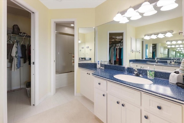 bathroom with tile patterned flooring, a spacious closet, an enclosed shower, and vanity