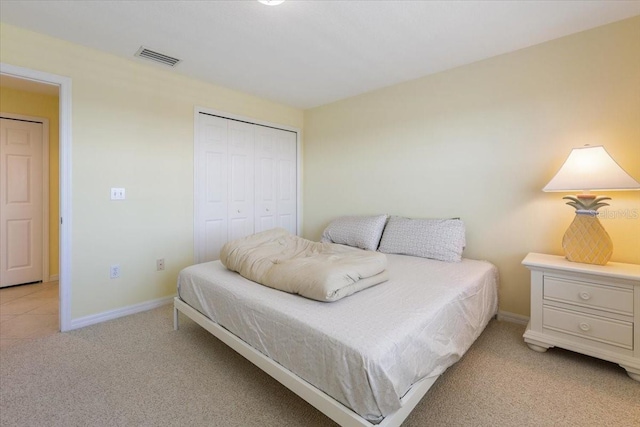 bedroom with light carpet, baseboards, visible vents, and a closet