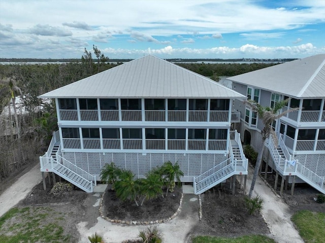 rear view of house with metal roof, stairway, and a sunroom