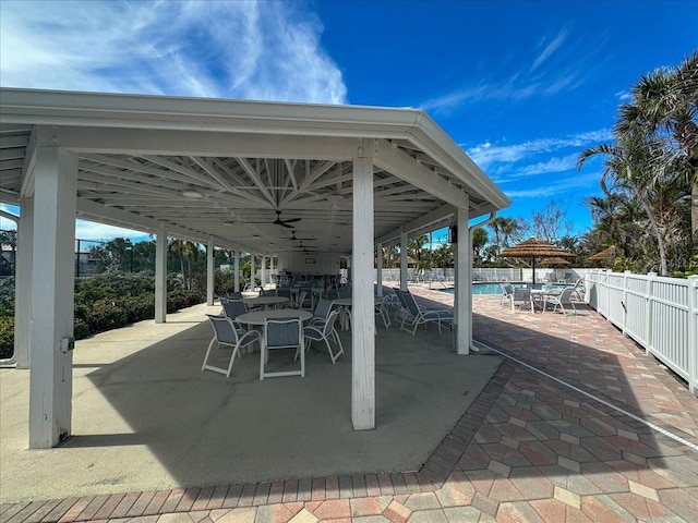 view of patio featuring outdoor dining area, fence, and a community pool