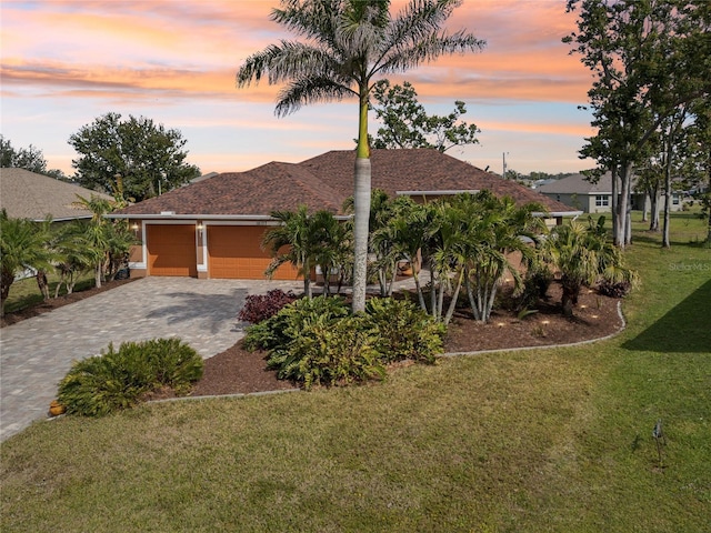 view of front of home with a garage, decorative driveway, and a lawn