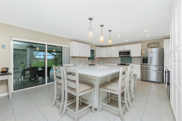 kitchen featuring a kitchen island, white cabinetry, light countertops, appliances with stainless steel finishes, and decorative backsplash