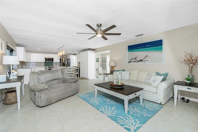 living area with light tile patterned floors, a ceiling fan, visible vents, and a textured ceiling